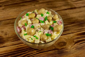 Potato salad with marinated mushrooms, sausage, onion and mayonnaise on wooden table