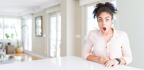 Wide angle of beautiful african american woman with afro hair In shock face, looking skeptical and...
