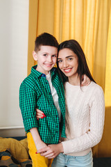 Portrait of mother and little son hugging smiling indoors.