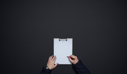 Businessman hands writing on white paper . Flat lay and top view with copy space on black background .business desk lifestyle concept.