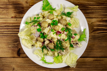 Potato salad with marinated mushrooms, eggs, red onion and mayonnaise on wooden table