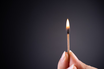 Close up woman hand holding a burning match.