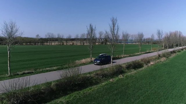 Aerial Shot of a Transporter driving. In the background is the ocean with the fehmarn sund bridge. Shot was made in northern germany. Good, windy weather conditions.