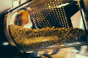 Roaster machine prepared coffee beans.  Process of coffee roasting in cafe. Ingridient for popular european drink. Brown bean inside box. Organic food. Close up shot.
