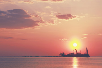 Obraz premium Silhouette of industrial ship and sunset over the sea