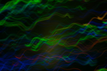 Blur multicolor wavy lines on dark background. Neon lights in motion. Bokeh lens flare glow.