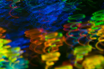 Fototapeta na wymiar Blurred neon lights in motion. Swirled thin multicolor lines on dark background. Lens flare effect.