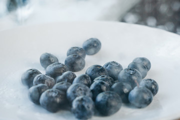 fresh blueberry berries on a white plate close-up. breakfast of wild berries. copy space