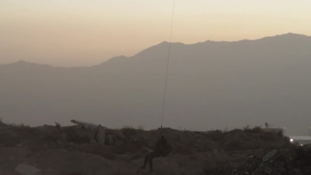 Soldier fast-ropes out of helicopter