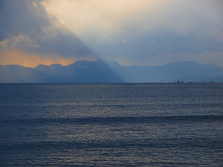 Sea where sunlight falls from cloudy sky