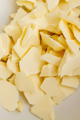Pieces of butter are in a bowl for mixing in the preparation of cookies