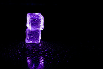 Purple ice cubes reflection on black table background.