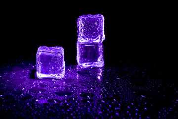 Purple ice cubes reflection on black table background.