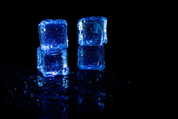 Blue ice cubes reflection on black table background.