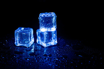 Obraz premium Blue ice cubes reflection on black table background.