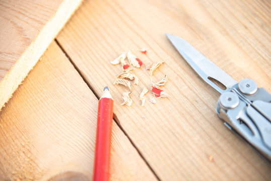 Background with tools. Pencil red sharpened with a folding knife lies on a wooden background