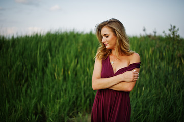 Naklejka na ściany i meble Blonde sensual woman in red marsala dress posing in the reeds.