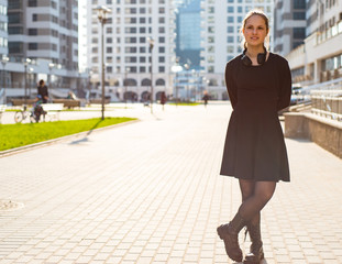 Outdoor portrait of young teenager brunette girl with long hair. girl on city in black dress