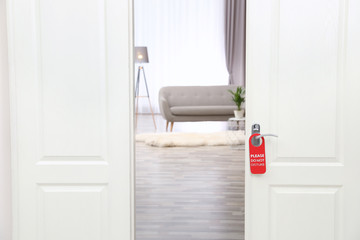 Fototapeta premium Open door with sign PLEASE DO NOT DISTURB on handle at hotel