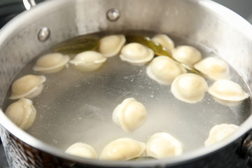 Closeup of metal stewpan with boiling water and dumplings. Home cooking