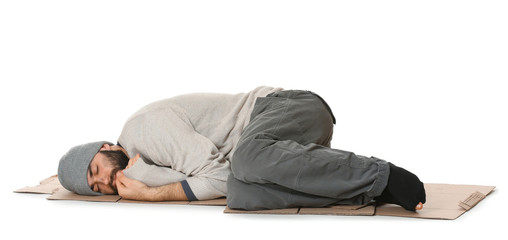 Poor homeless man lying on cardboard, white background