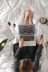 Woman and laptop with beauty blogger site on bed, top view