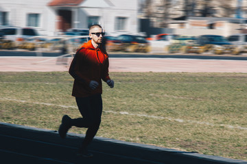 running man training outdoors with sunglasses. runner at the stadium on a sunny day. shot in motion - obrazy, fototapety, plakaty