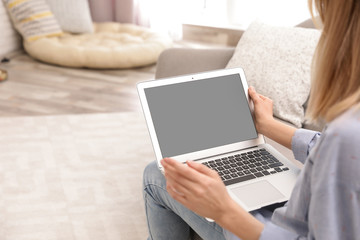 Fototapeta premium Young woman using video chat on laptop in living room, closeup. Space for design