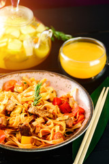 Pork with vegetables and rice noodles close up on a plate. horizontal