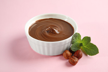 Dessert bowl with sweet chocolate cream, hazelnuts and mint on color background
