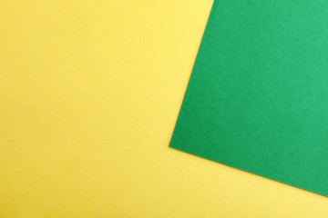 Green and yellow paper sheets as colorful background, top view