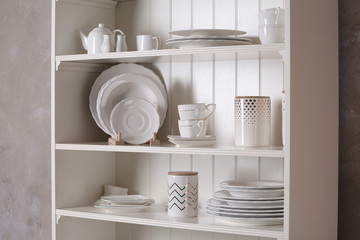 Stylish storage stand with different ceramic dishware at home