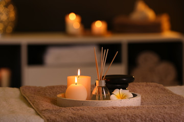 Burning candles and aromatic reed freshener on table in spa salon