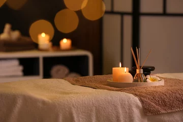 Fototapeten Burning candles and aromatic reed freshener on table in spa salon, space for text © New Africa