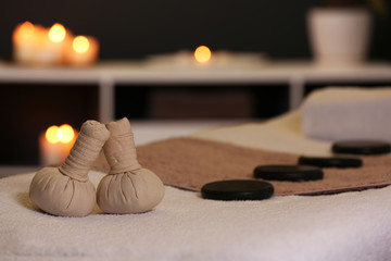 Herbal compresses and stones on massage table in spa salon. Space for text