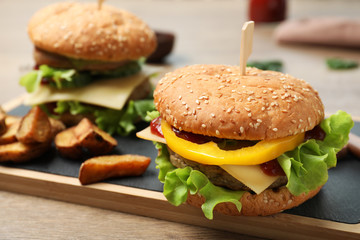 Board with delicious hamburger on table. Space for text