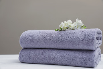 Stack of fresh towels with flowers on table. Space for text