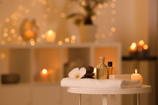 Spa supplies, burning candle and flower on table in beauty salon, space for text