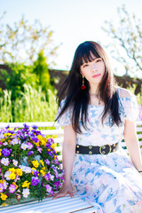 ベンチに腰掛ける白いワンピースの女性