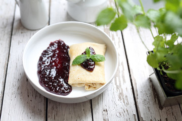 Pancakes stuffed with white cheese with dark fruit jam.