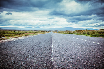 Trip or adventure: Abandoned, dramatic road in Scotland, cloudy sky.