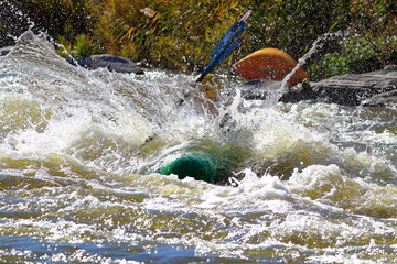 Two adult man paddling a kayak among rapids in rough river. Whitewater kayaking in Ukraine