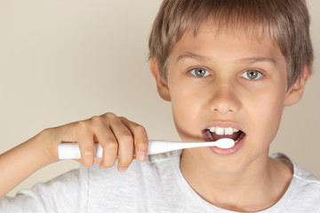 Kid brushing teeth with white electric toothbrush
