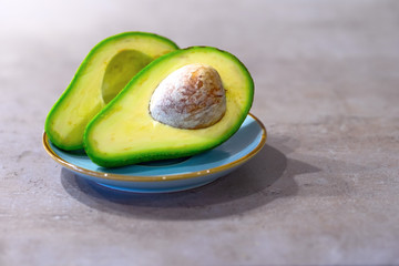 Half avocado with bone on gray kitchen countertop. Place for text.