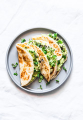 Avocado eggs greens salad paratha flatbread quesadilla on a light background, top view