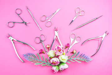 Manicure tools on a pink background decorated with flowers. Beauty concept. Place for text.