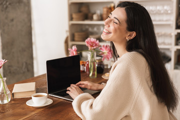 Photo of attractive brunette woman 20s using laptop computer in kitchen at home