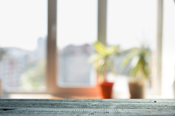 Wood table top on blur of window glass and abstract green from garden with city view in the morning background. For montage product display