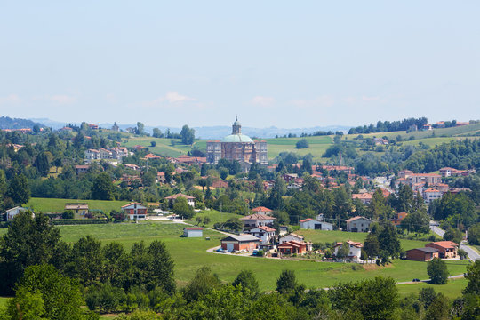 Sanctuary of Vicoforte and town with buildings, trees and meadows in Piedmont, Italy