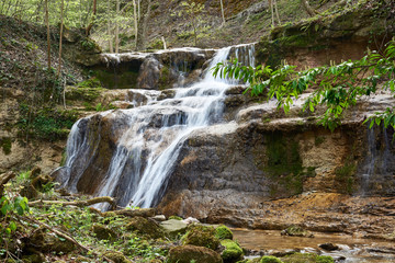 Fototapeta na wymiar Dorfbach mit Wasserfall im Erlenbacher Tobel, verwischtes Wasser, Stufen, Aeste, Steine, Moos, grüne Blätter